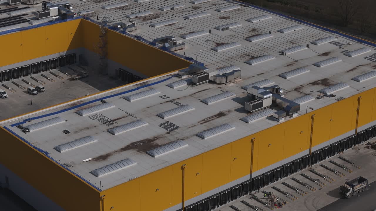 Logistics warehouse near Autostrada A1 in Po Valley Emilia Romagna Italy with storage yard, truck loading area and industrial distribution infrastructure, drone lateral pan to left