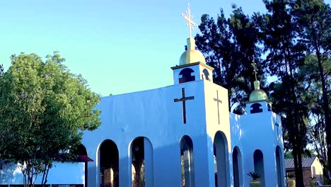 una toma reveladora del edificio de la iglesia ortodoxa blanca rodeada de árboles y un cielo despejado