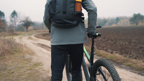 hombre atleta montando una bicicleta de montaña por una carretera en el campo