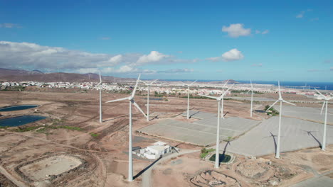 Vista-Aérea-En-órbita-Sobre-Un-Campo-De-Turbinas-Eólicas-En-Un-Paisaje-Desértico-En-La-Isla-De-Gran-Canaria-Y-En-Un-Día-Soleado