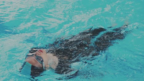 Una-Joven-Nadadora-Asiática-Practicando-Estilo-Espalda-En-La-Piscina.