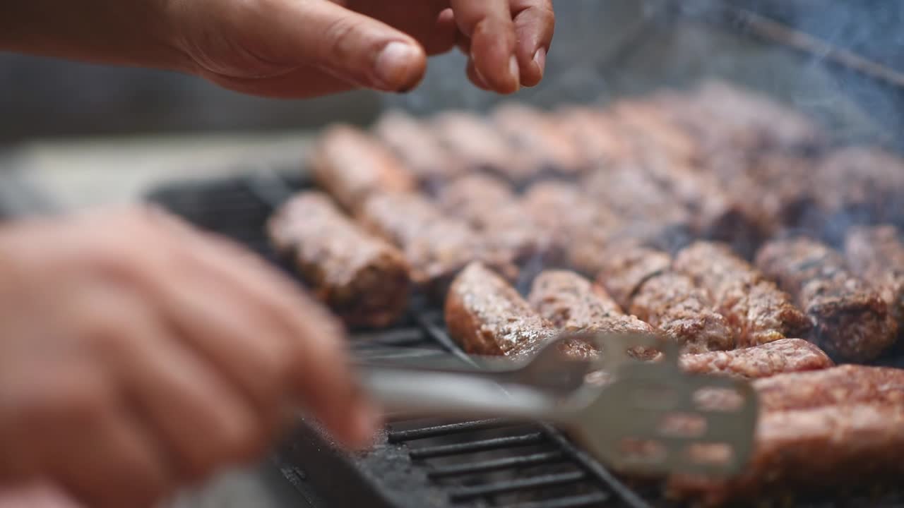 Man preparing sausage on the grill using tongs. Slow motion shot. Close up. Slow motion