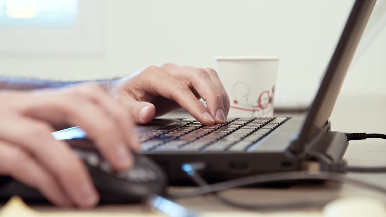 Mani di un uomo che digitano sulla tastiera di un computer portatile.