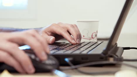 manos del hombre escribiendo en un teclado de computadora portátil