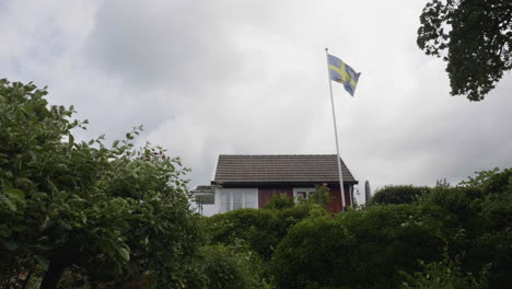 swedish flag flying high on a flagpole at a summer cabin, low angle view