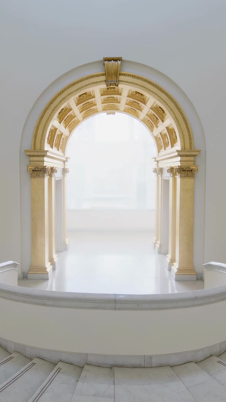 Video verticale: La telecamera si allontana rivelando un arco dorato e colonne in un atrio per mostrare una balaustra.