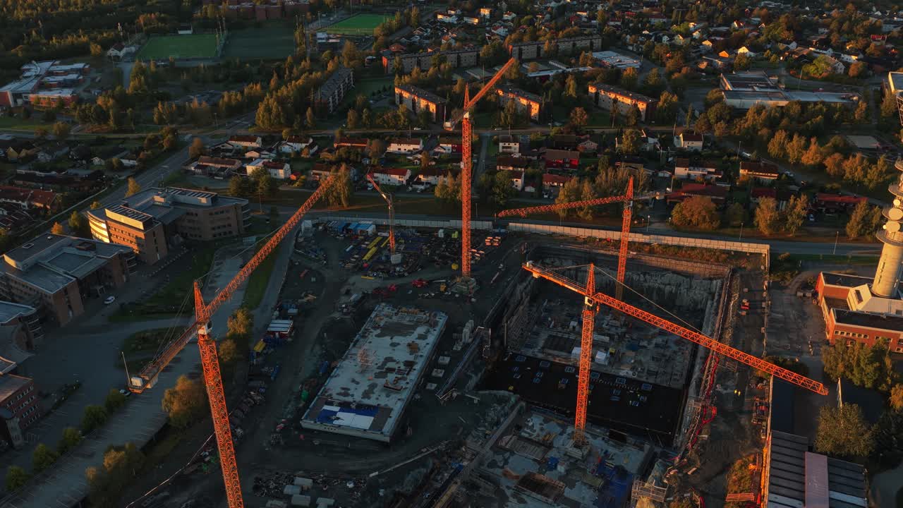 Letecký záběr staveniště s velkými jeřáby v ranním světle, Norsko