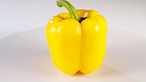 cerrar un pimiento amarillo girando sobre un fondo blanco