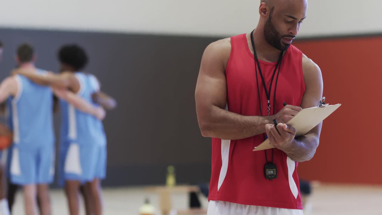 retrato de un feliz entrenador de baloncesto biracial en una cancha cubierta, en cámara lenta