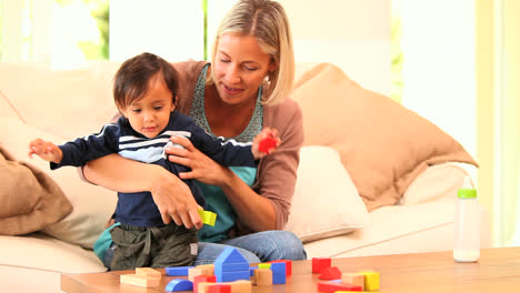 Young-mother-on-sofa-playing-with-baby-