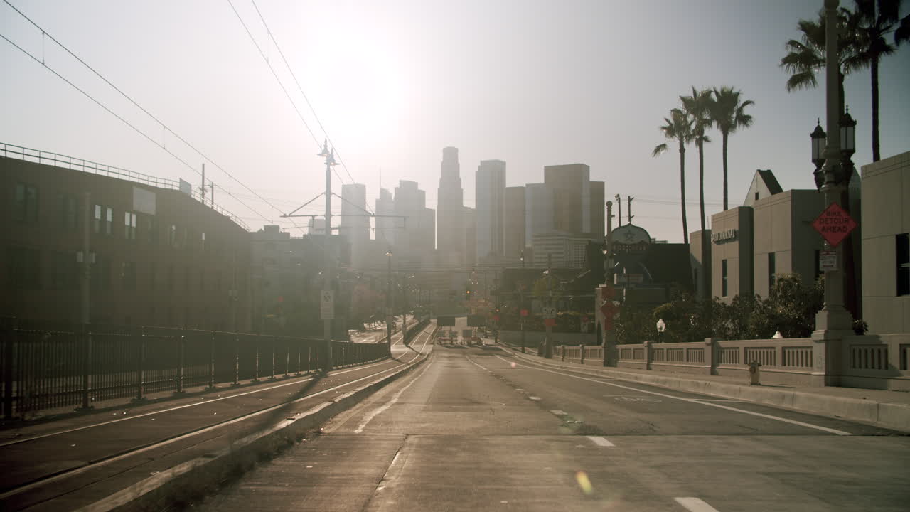 Hazy urban street leading to a city skyline with palm trees