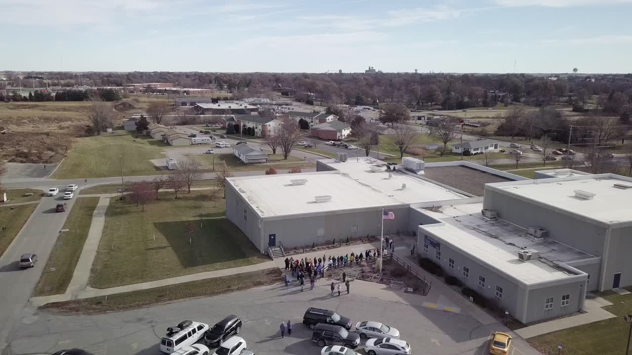 Aerial Drone Footage Of An American Flag Flying In The Breeze And People Gathered Outside Of A Performing Arts Center, Iowa