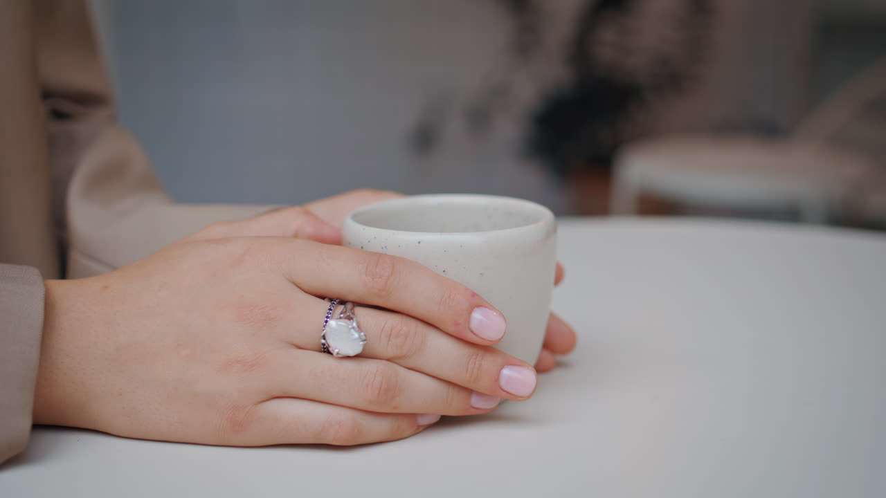 mujer con las manos sosteniendo una taza de café en una acogedora cafetería. mujer de negocios desconocida