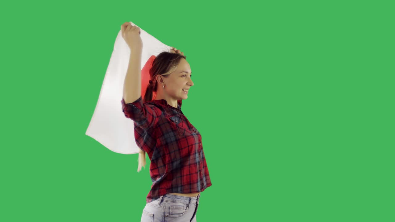 una mujer feliz sosteniendo una bandera japonesa y bailando en la pantalla verde de chroma key.
