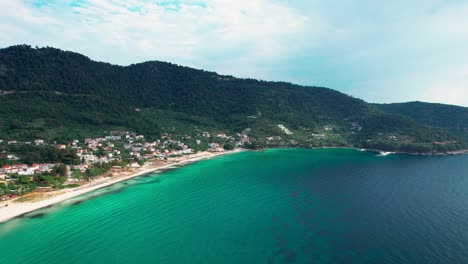 Drone-View-Of-Golden-Beach-With-Towering-Mountain-Peaks,-Beautiful-Beachfront-And-Lush-Vegetation,-Vivid-Colors,-Thassos-Island,-Greece,-Europe