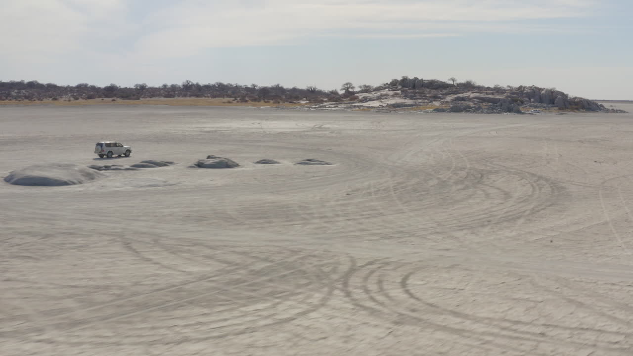 보츠와나의 쿠부 섬을 향해 막가디카디 소금 팬에서 운전하는 흰색 suv 사파리 차량