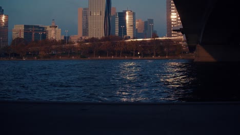 Landscape-view-to-the-bridge-of-Vienna,-Reichsbrücke,-Danube-during-Dusk-,-golden-hour-while-people-passing-by