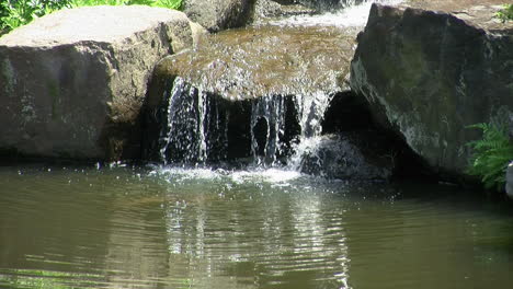 el agua fluye por las rocas hacia el estanque