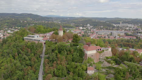 vista aérea amplia órbita alrededor de la histórica torre glokenturm en la cima de una colina en el schloßberg de graz con vistas al horizonte de la ciudad