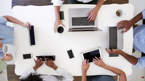 Group-work-on-computers-with-phones,-overhead-shot,-slo-mo