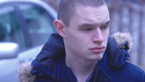 a man wearing winter coat standing outside with falling snow in canada - close up shot-1