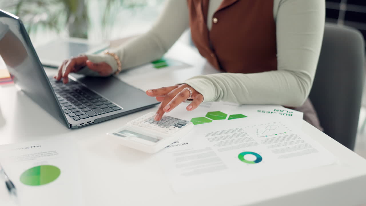 Woman's Hands Typing on Laptop and Using Calculator with Business Documents