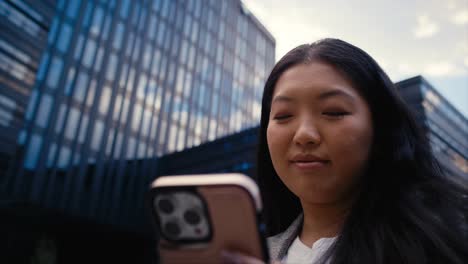 Low-Angle-Ansicht-Einer-Fröhlichen-Geschäftschinesin,-Die-Auf-Dem-Mobiltelefon-Surft