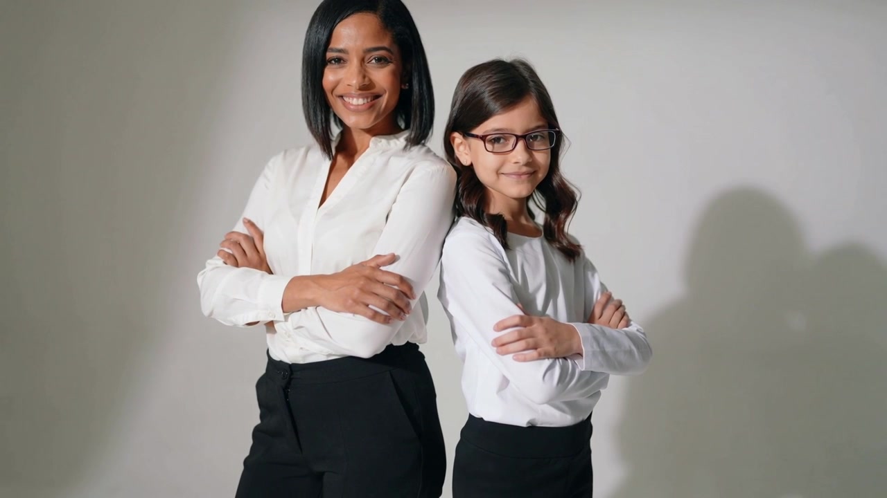 Comienza la sesión de fotos, mujer y niño posando con los brazos cruzados en estudio, con camisetas blancas, el niño con gafas.