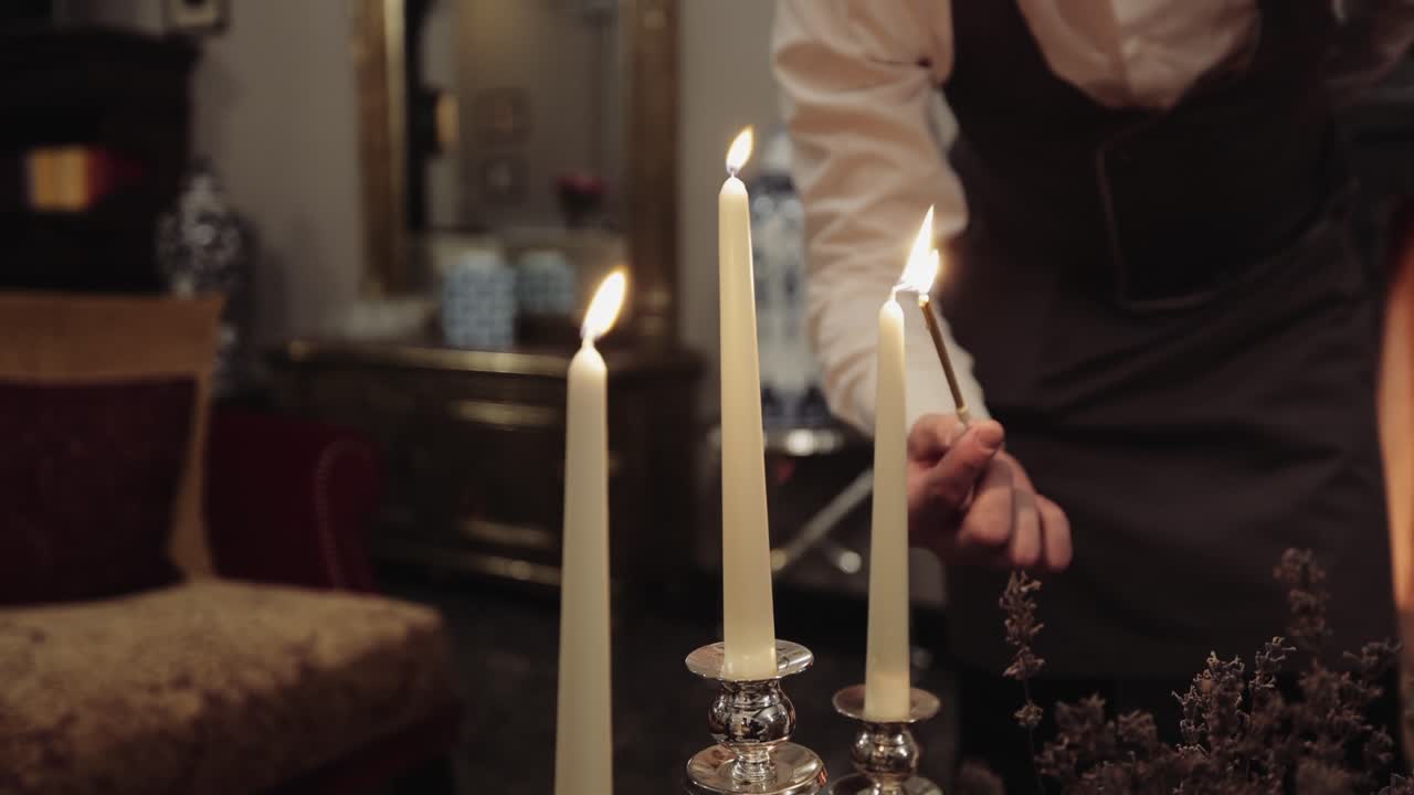 A person lights elegant taper candles, creating a warm and inviting ambiance indoors
