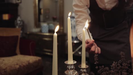 a person lights elegant taper candles, creating a warm and inviting ambiance indoors