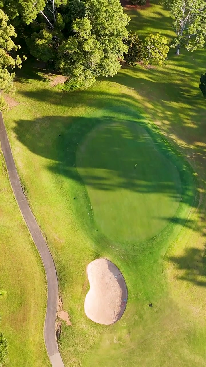 Prospettiva aerea da drone di un vivace fairway di campo da golf con sentieri tortuosi e bunker.