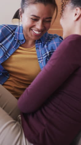 vertical video of happy biracial female couple embracing and talking in slow motion