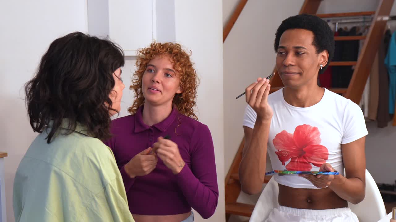 Three people in a room applying makeup and talking