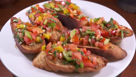 Köstliche-Bruschetta,-Dekoriert-Mit-Leckerem-Belag-Auf-Einem-Weißen-Drehteller,-Nahaufnahme