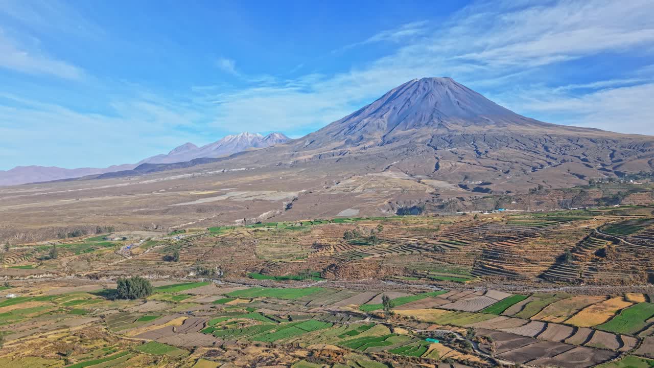 Filmato aereo che sale sopra il paesaggio andino con il vulcano Misti che domina in primo piano, perfettamente allineato con il Chachani in lontananza vicino ad Arequipa, Perù
