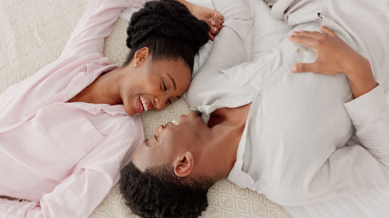 Happy black couple bonding in bed, talking