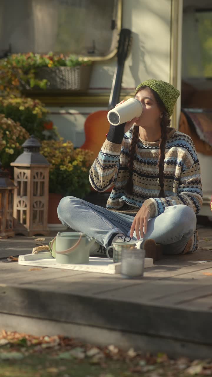 mujer disfrutando de una bebida caliente al aire libre por un campista