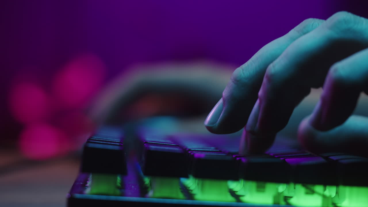 Nærbillede af en hånd, der taster på et baggrundsbelyst tastatur med neonlys