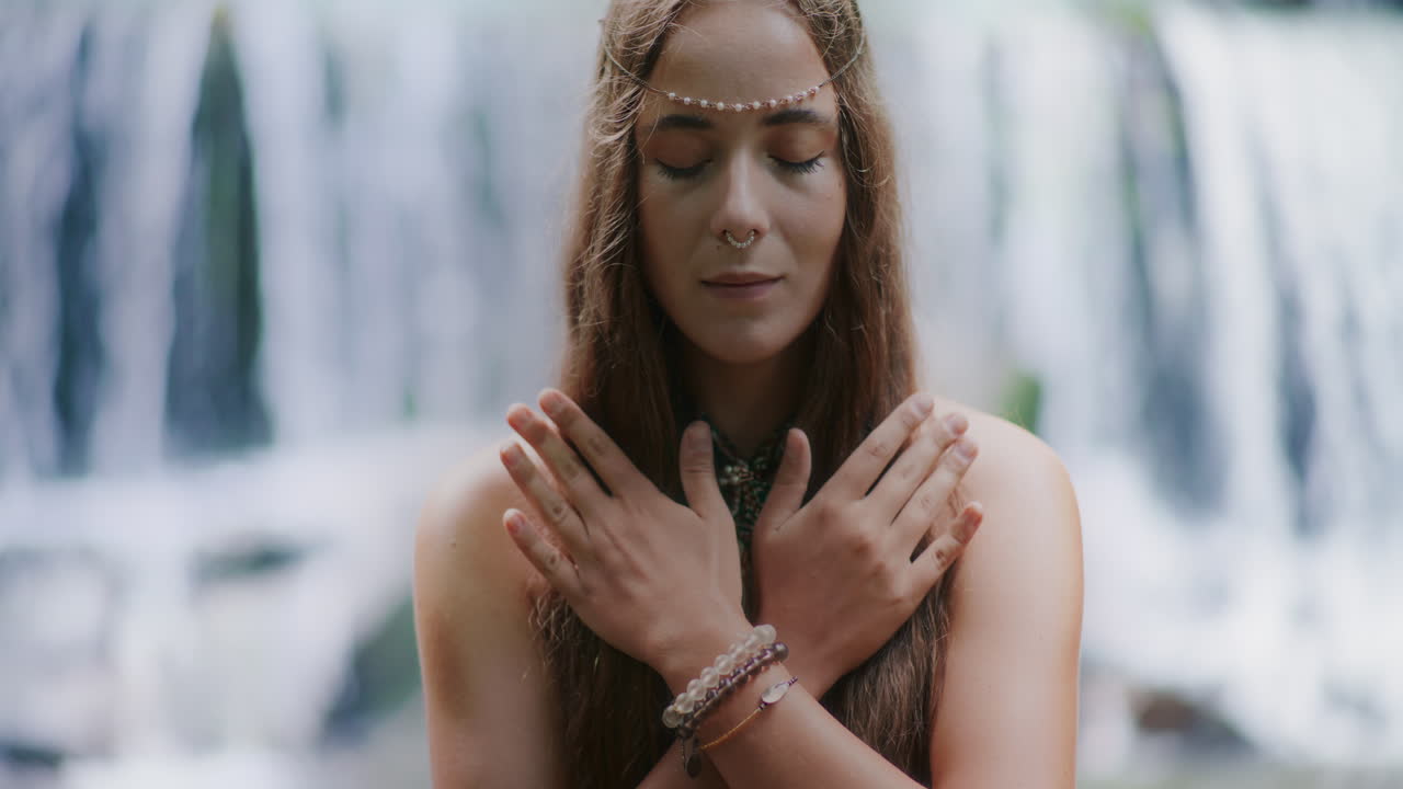 폭포 앞에서 명상하는 여성은 영감과 평화를 찾고 있습니다.