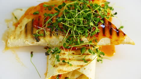 delicious dish in the restaurant. yummy pita poured with sauce on table.tasty meal decorated with green sprouts. ready to eat. close-up.