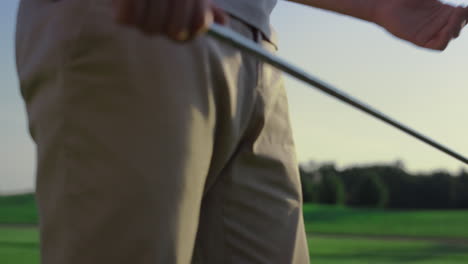 Golf-player-swinging-club-putter-on-sunset-field.-Golfer-stressing-on-sport-game