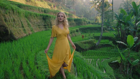 beautiful woman walking in rice paddy wearing yellow dress exploring lush green rice field exotic vacation in bali indonesia