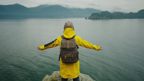 woman hiking on coastal cliff with rain jacket
