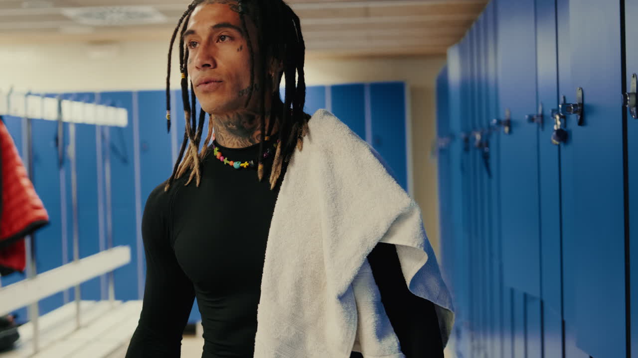 Athlete with Dreadlocks and Tattoos Walking in a Locker Room