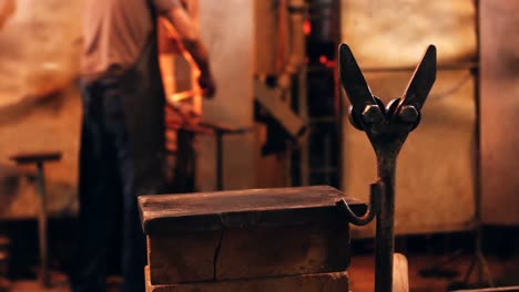 mid section of glassblower reheating and shaping a molten glass