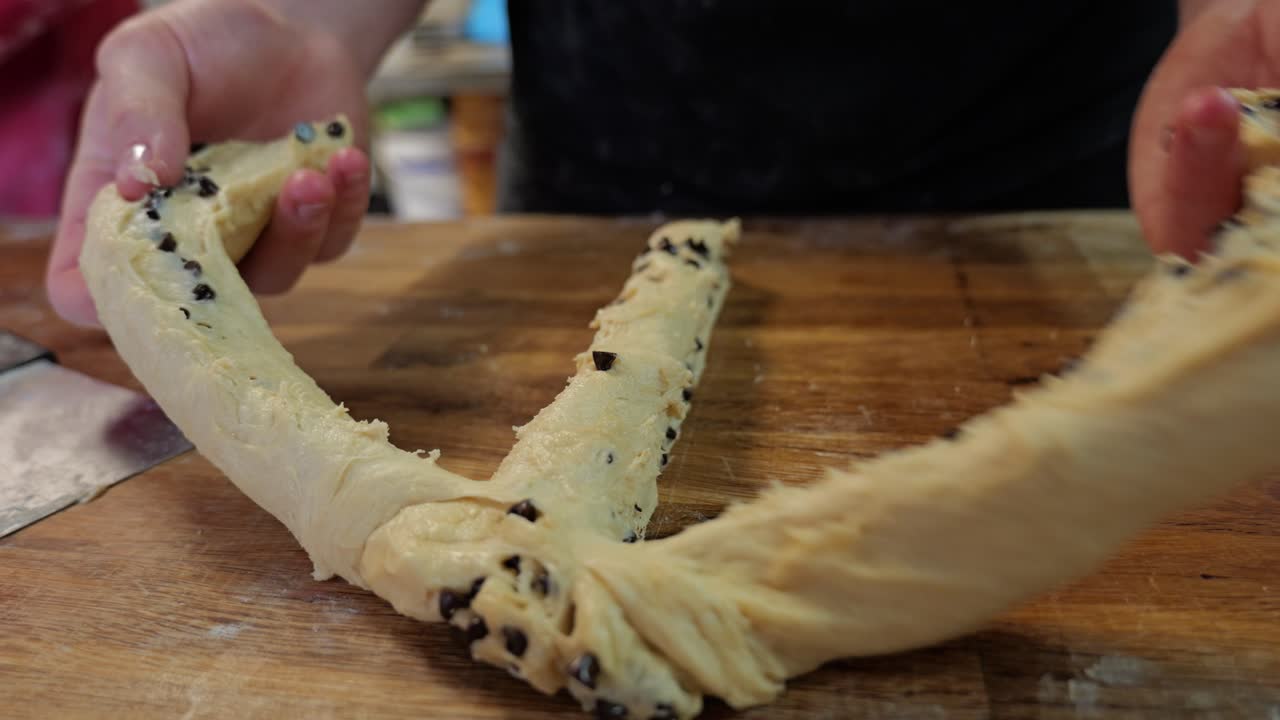 Il panettiere taglia e prepara le porzioni di impasto a mano prima di intrecciare.