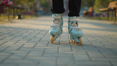 a close-up view of a person s feet wearing rollerblades, gliding on a paved path in a park. the focus on the rollerblades emphasizes the motion and activity, with the background softly blurred