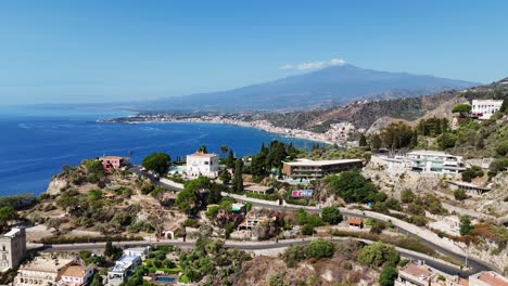 scenic view of a coastal town with houses and lush greenery, mountain in the distance