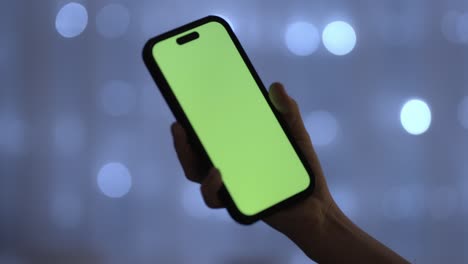 hand of female kid holds phone with green screen chroma key