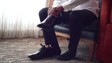 man putting shoe on his left leg preparing for his wedding